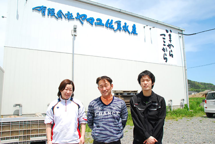 ヤマユ佐勇水産の工場前で。佐藤さん（中）と妻の央子（ようこ）さん（左）長男の勇太さん（右）